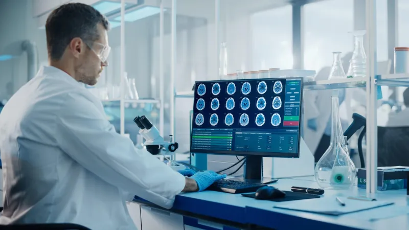 Mlody naukowiec w laboratorium analizuje obrazy mozgu na monitorze komputera
